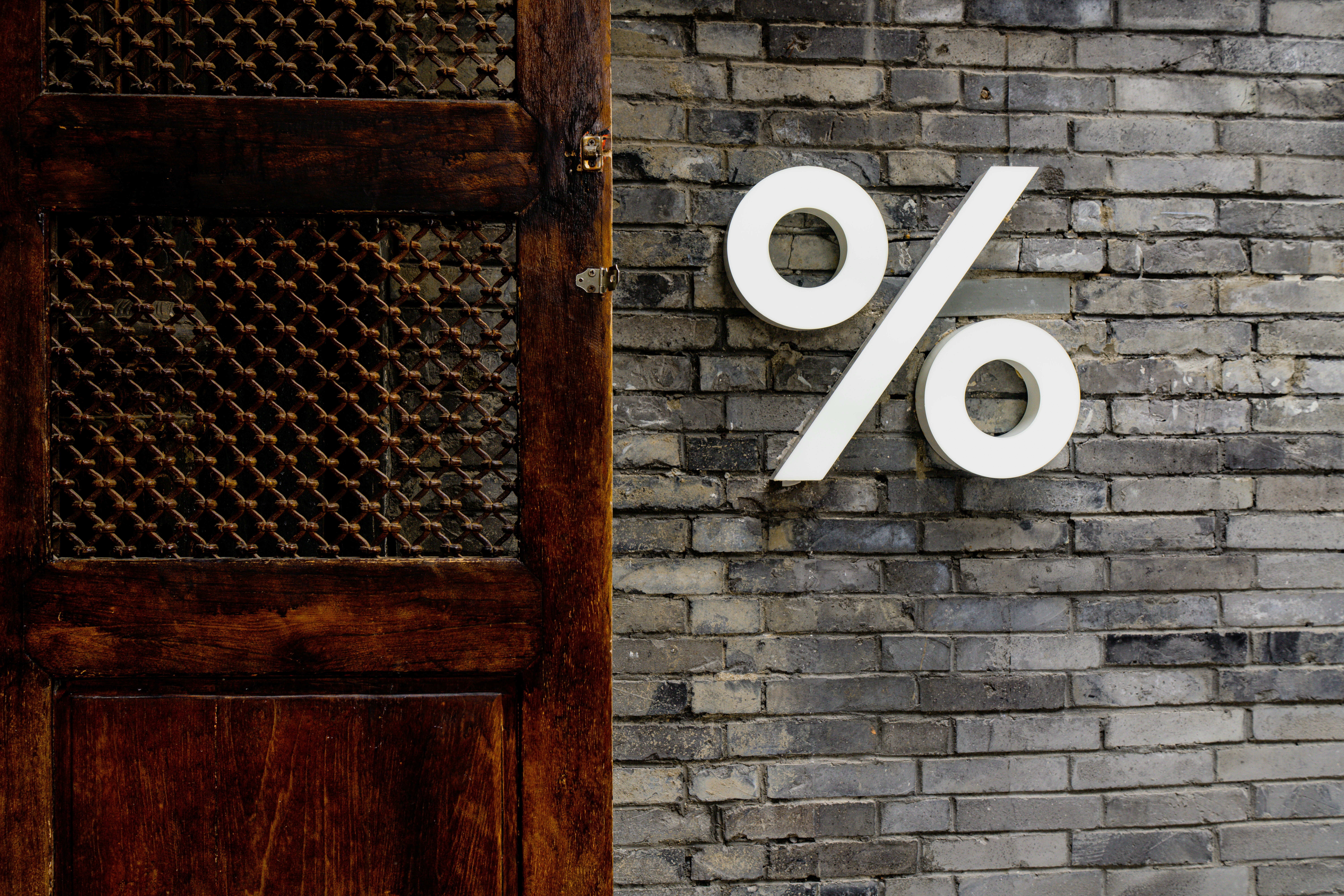 white-percentage-sign-on-a-brick-wall - declan-sun (unsplash)./pho
