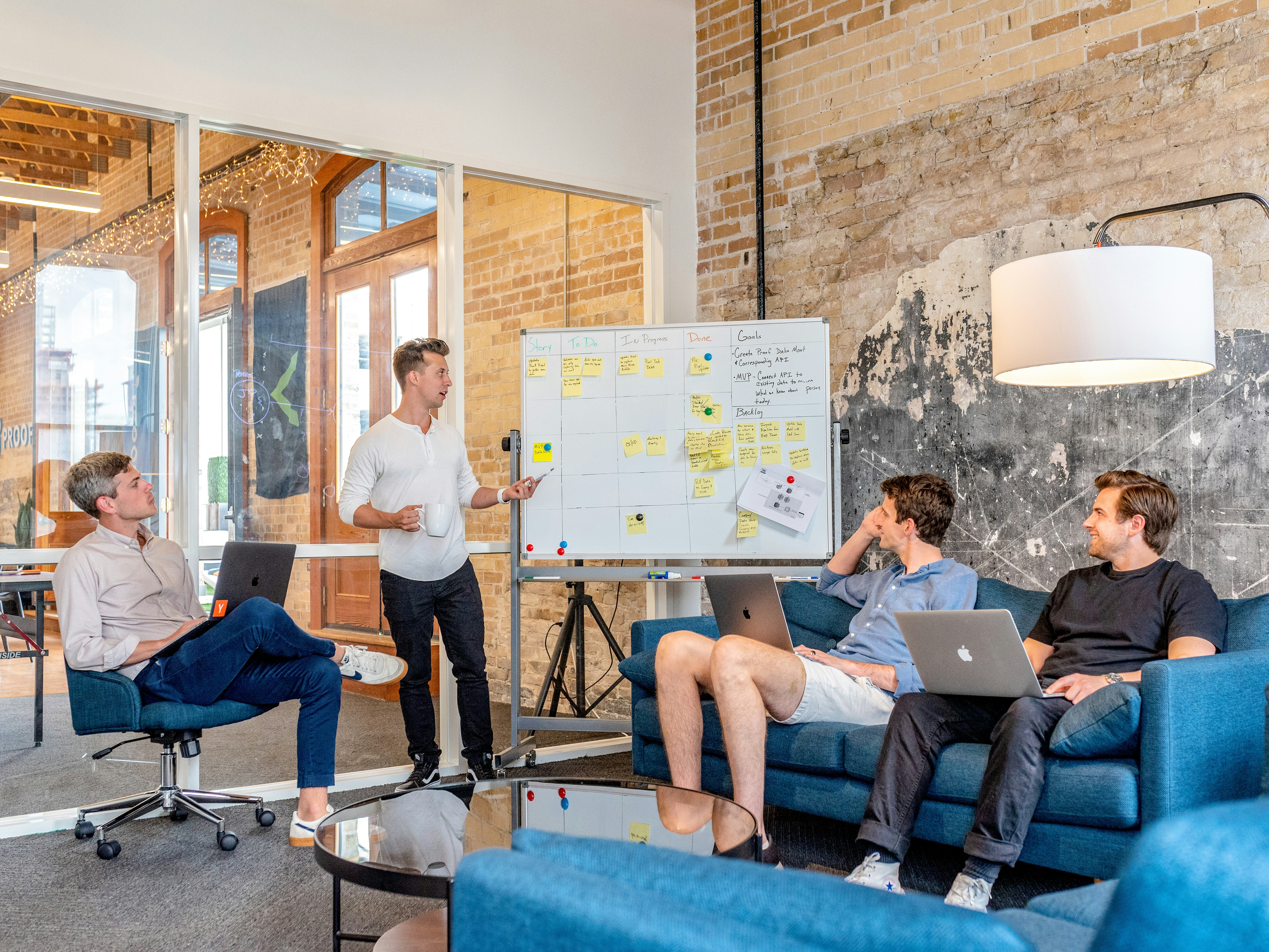 three-men-sitting-while-using-laptops-and-watching-man-beside-whiteboard - austin-distel (unsplash)./pho